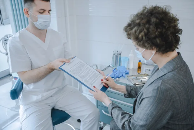 A medical professional and patient reviewing documents in a clinic setting. Documented procedures: why this site avoids photo-based claims, and what a real record contains
